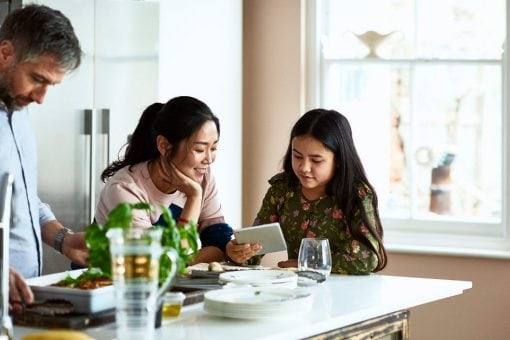 A family talks together as they stand around a kitchen island.