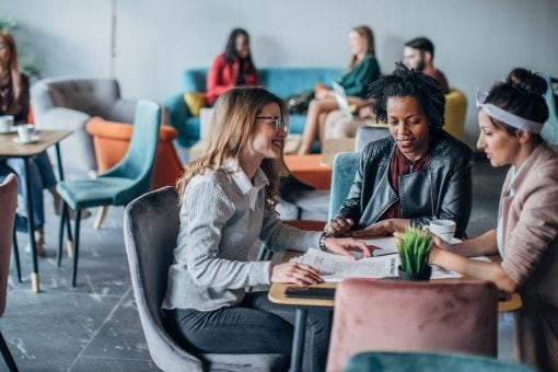 Three women sit at a table in a cafe.