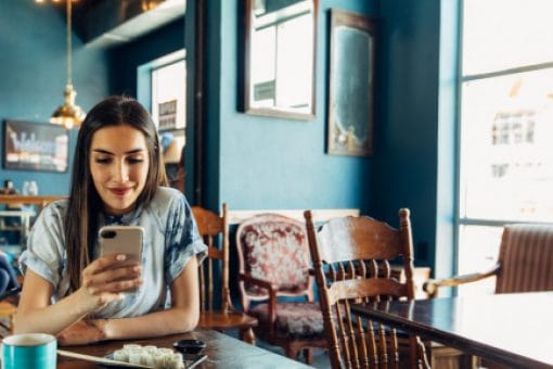 Young woman smiles while looking at mobile phone.