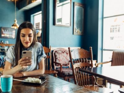 Young woman smiles while looking at mobile phone.