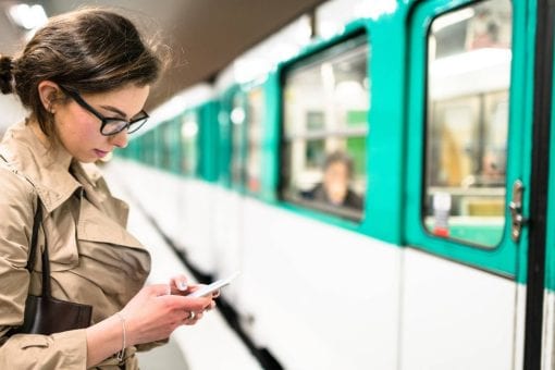 Woman on her phone stands next to a commuter train.