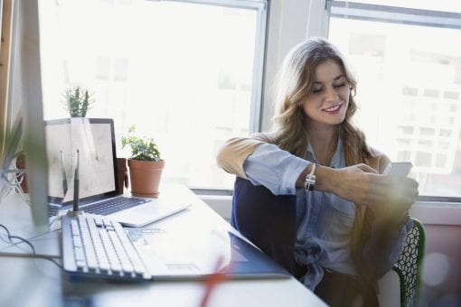 A happy young woman browses on her phone.