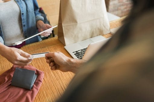 Customer hands store clerk their credit card.