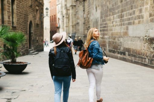 Two women sightseeing near stone buildings
