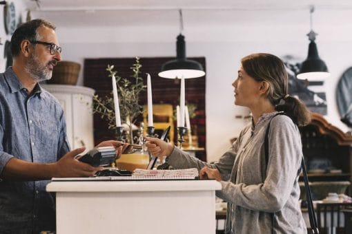 A woman hands a store clerk her credit card.