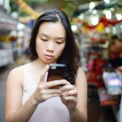 Woman at street market looks at her phone.