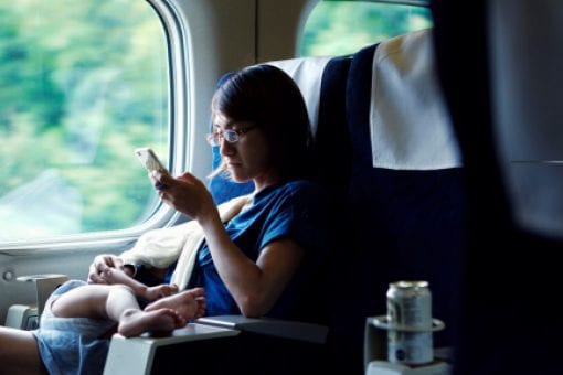 A young mother holds her baby and browses on her phone.