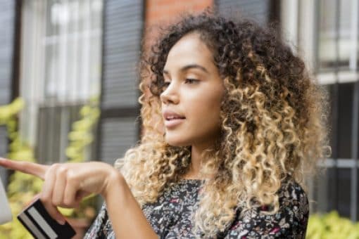 Woman using a tablet and holding a credit card.