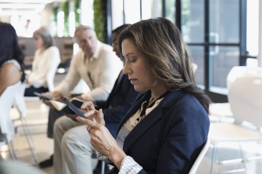 A woman sits in an audience as she uses a mobile phone.