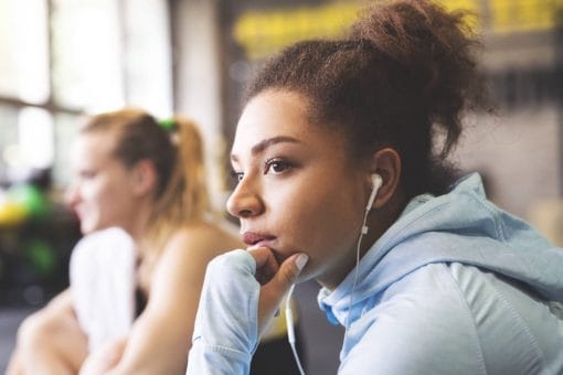 Woman in hoodie with headphones on stares off into the distance.