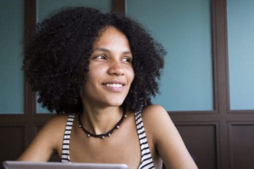 Woman smiles as she holds a digital tablet.