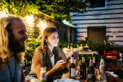 Young people enjoy a meal around a table in an urban backyard.