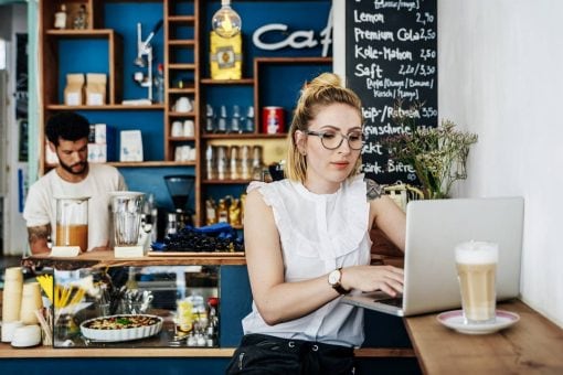 Young woman works at a laptop while sitting in a café.