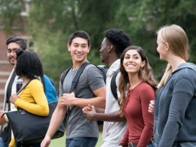 Group of diverse students walk and talk together.