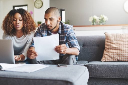 Young couple sits at home on their couch reviewing their credit scores.