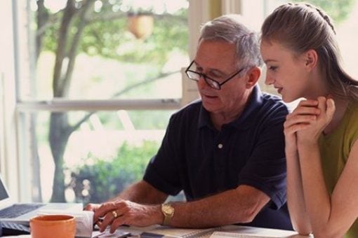 Dad and daughter sit together at a desk.