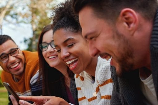 A group of young people in a park laugh together.