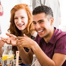 Man laughs as he sits with friends during meal.
