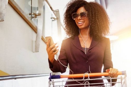 A young woman listens to music on her phone while shopping at a store.