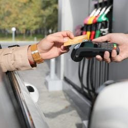 A driver uses their credit card at a gas pump to pay for gas and earn rewards.