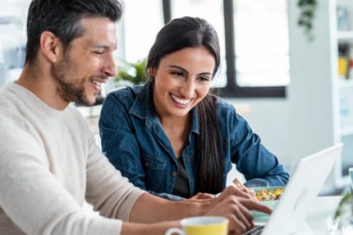 Smiling couple looks at laptop screen in their home