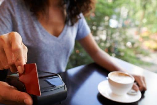 A woman in a café swipes her credit card in a portable card reader.