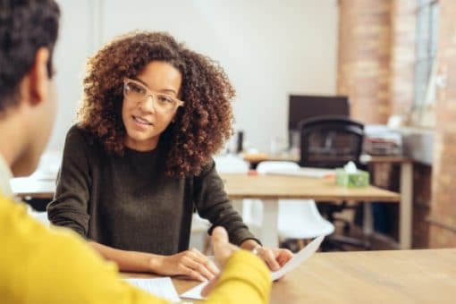 A woman and a man sit at a table talking about college gap year options.