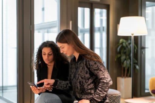Two women looking down at a cellphone.