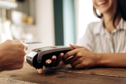 Man making a contactless credit card payment at a cash counter.