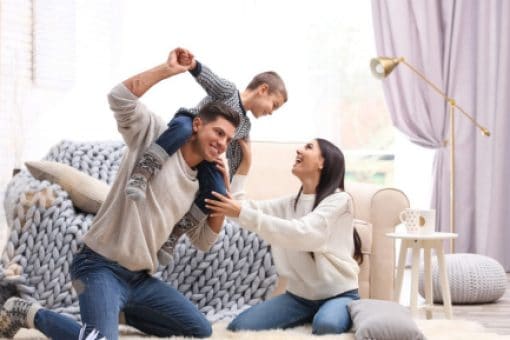 A man carries his son on his shoulder while his wife looks on.