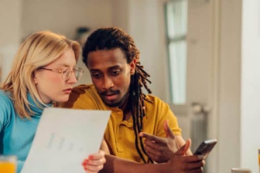 A man and a woman sit at a table reviewing their bills.