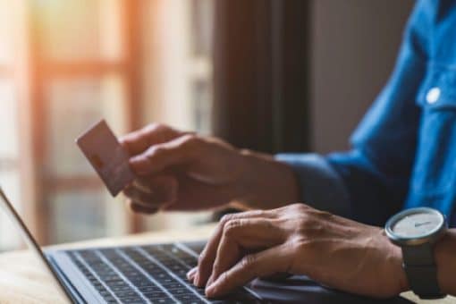 Close-up of hands typing on laptop and holding a credit card