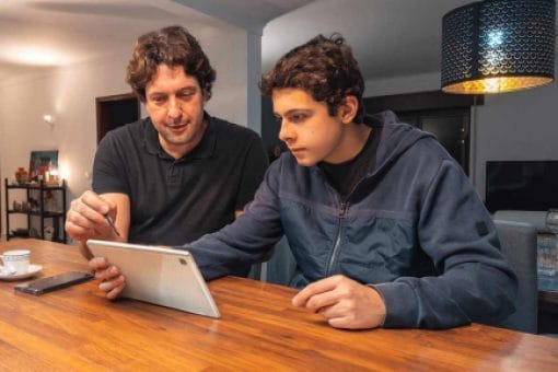 A father and teenage son look at a tablet screen together to compare credit cards.