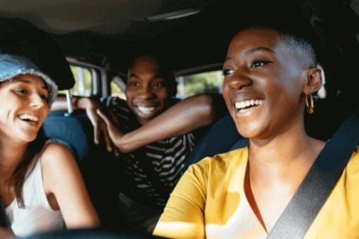 Three college students have fun in a car on a road trip.