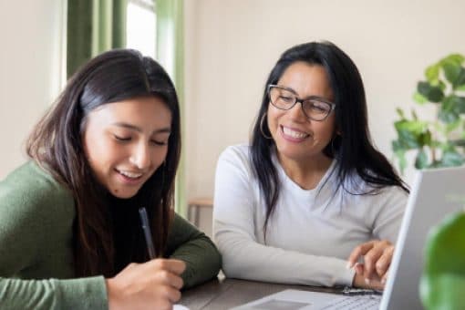 A mother helps her college aged daughter apply for a credit card.