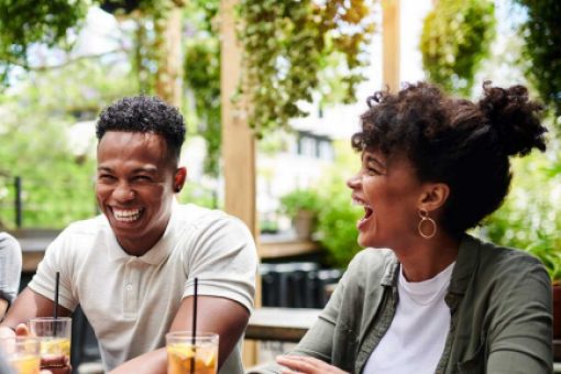 A group of friends enjoy iced tea on a sunny balcony in the city.