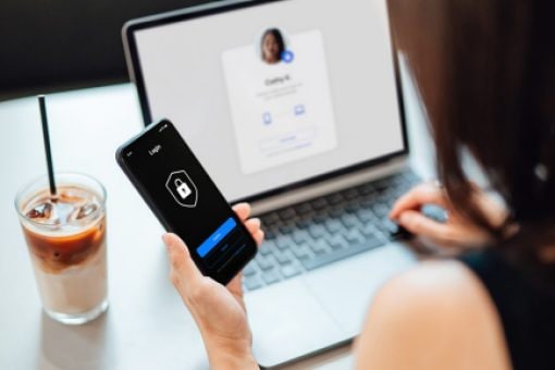 A woman uses her phone for multi-factor authentication to log in to a secure account on her laptop.