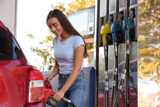 A woman filling up a car at a gas station.