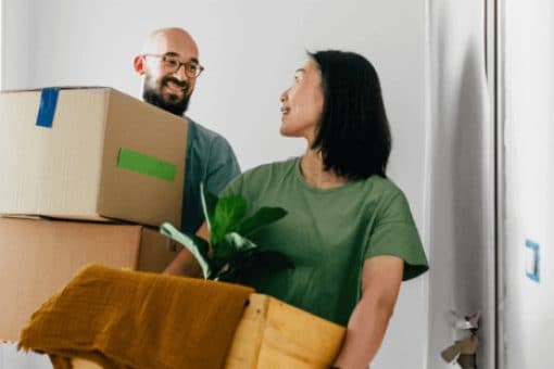 A man  and woman carry moving boxes.