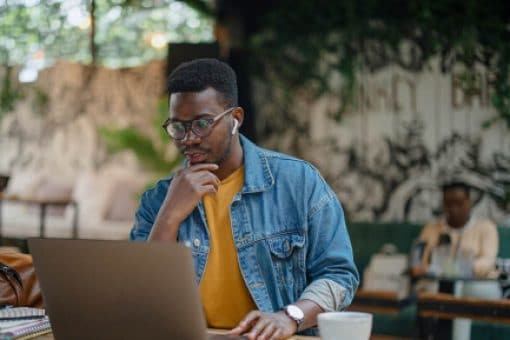 Man working on a laptop in a café with a coffee cup on the table.