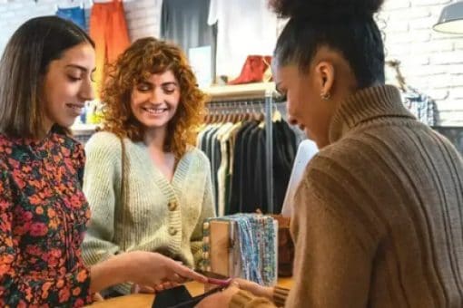 A woman uses her digital wallet to make a purchase at a clothing boutique.