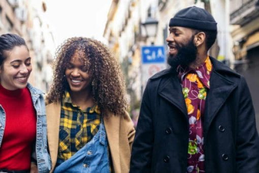 Three people walking down a street laughing together.