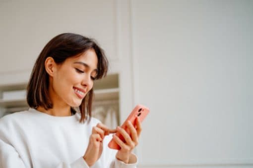 A woman smiling and checking her mobile phone.