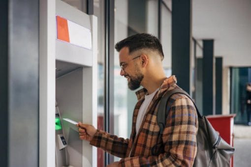 A person uses a credit card at an ATM.