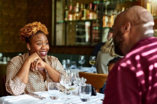 Smiling woman enjoying a conversation with a man at a restaurant.