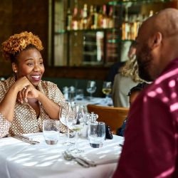 Smiling woman enjoying a conversation with a man at a restaurant.