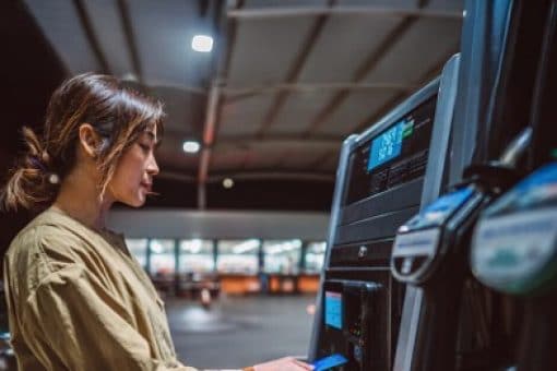 A woman uses her credit card to pay for gas at the pump.
