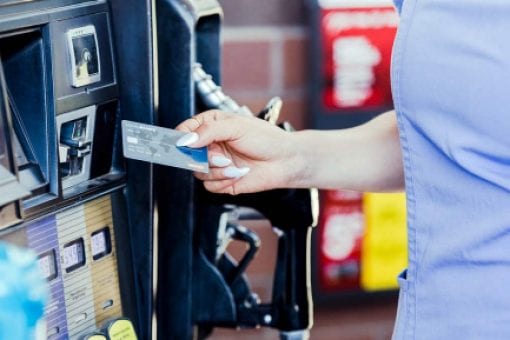 A driver uses their credit card to pay for fuel at the pump.