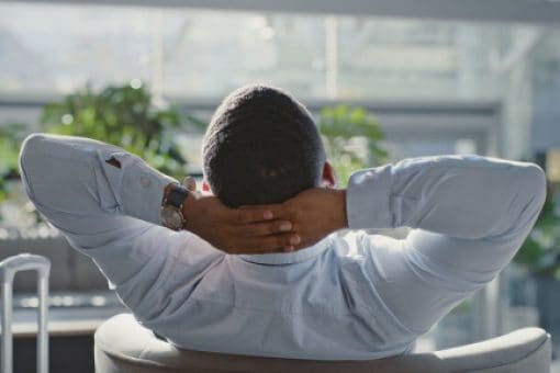 A man sitting and relaxing in an airport lounge chair.