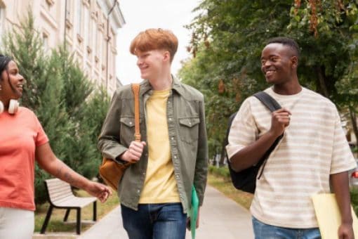 Three happy students walking outside at their university